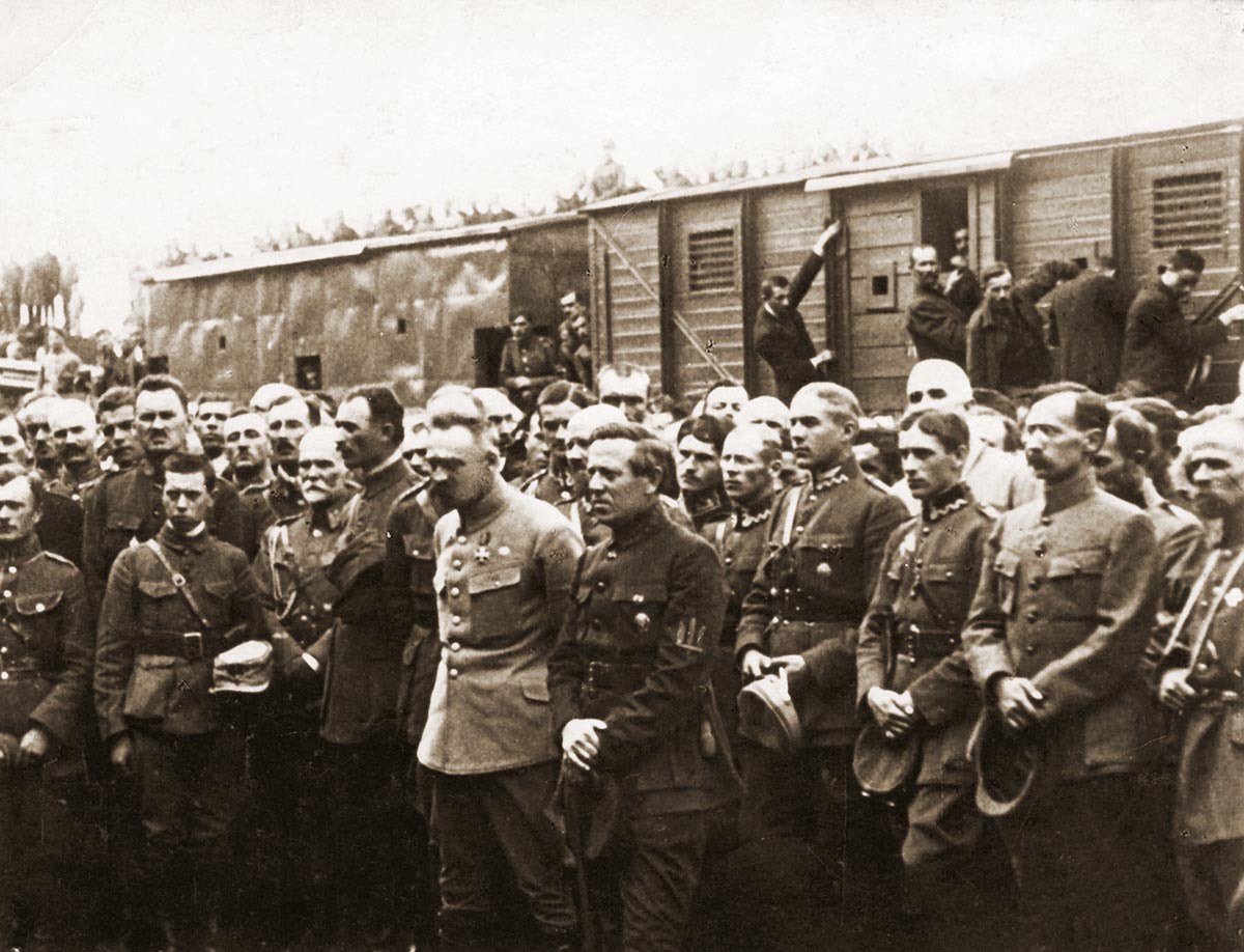 Sepia photograph from 1920: rows of Polish and Ukrainian officers standing in front of railway wagons, soldiers sitting on the roofs behind them.